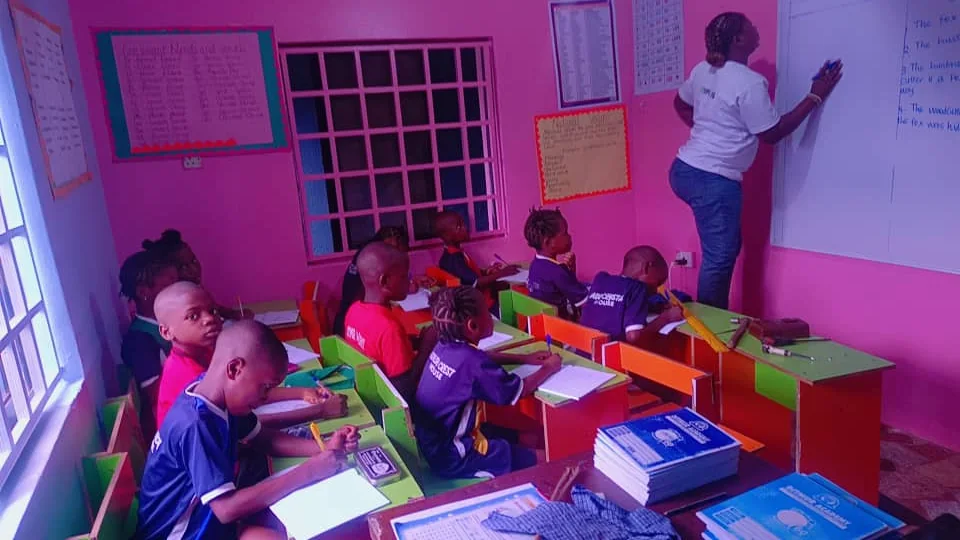 Teacher at a whiteboard while pupils work at colourful classroom desks
