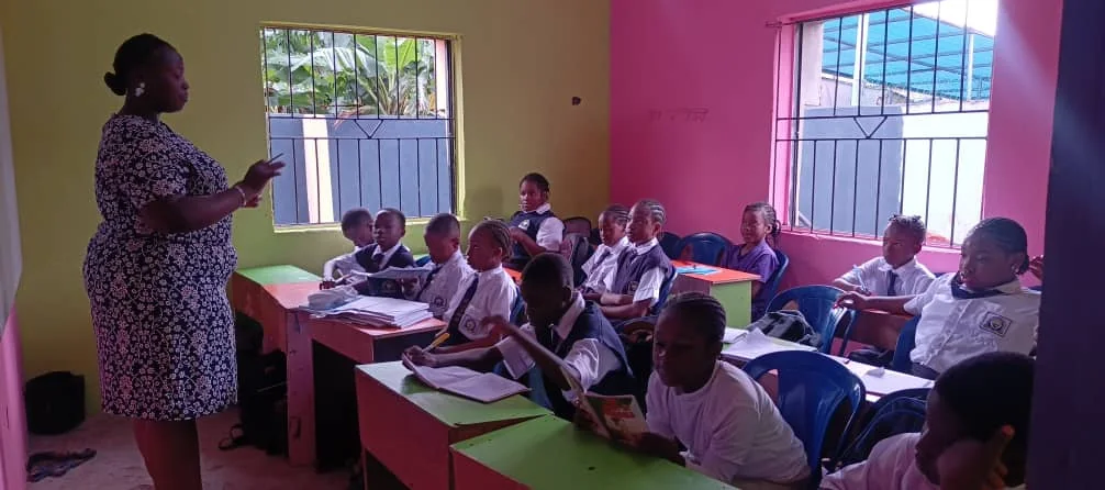 Students at desks listening to a teacher during a classroom lesson